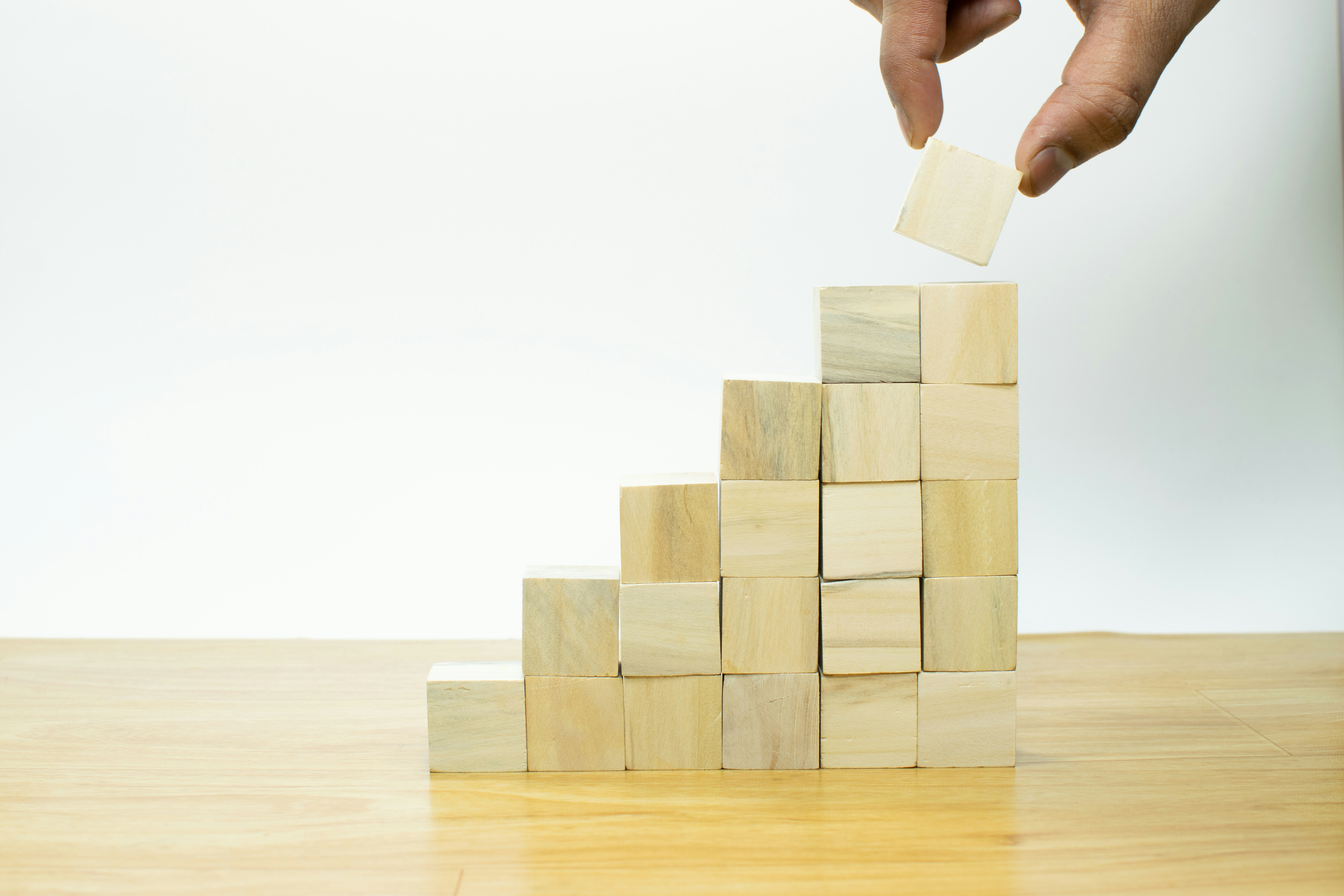 Wooden blocks stacked into rising steps — building wealth through property capital growth