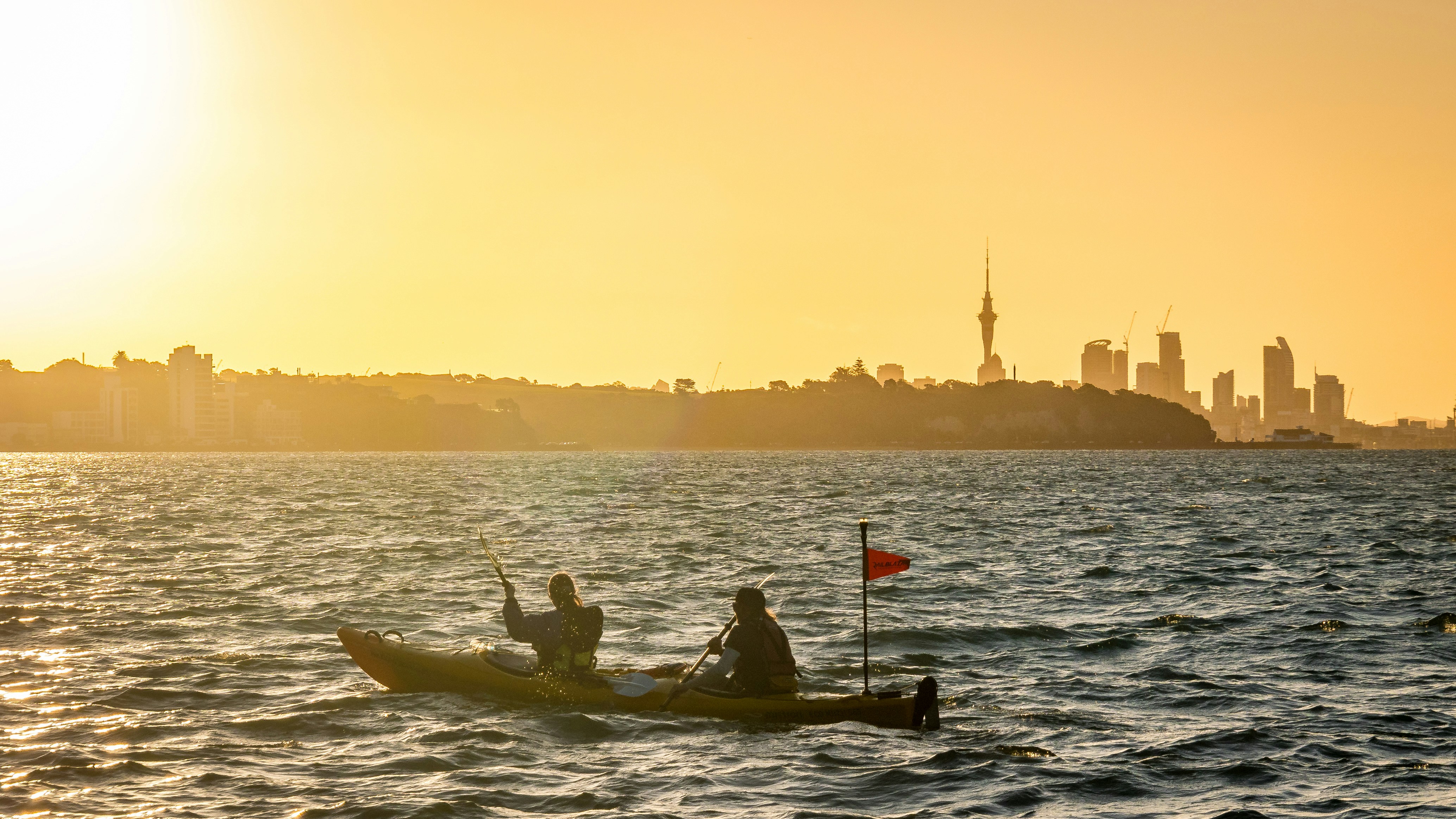 Auckland's skyline and Sky Tower at sunset across the harbour — a guide to Auckland rental yields