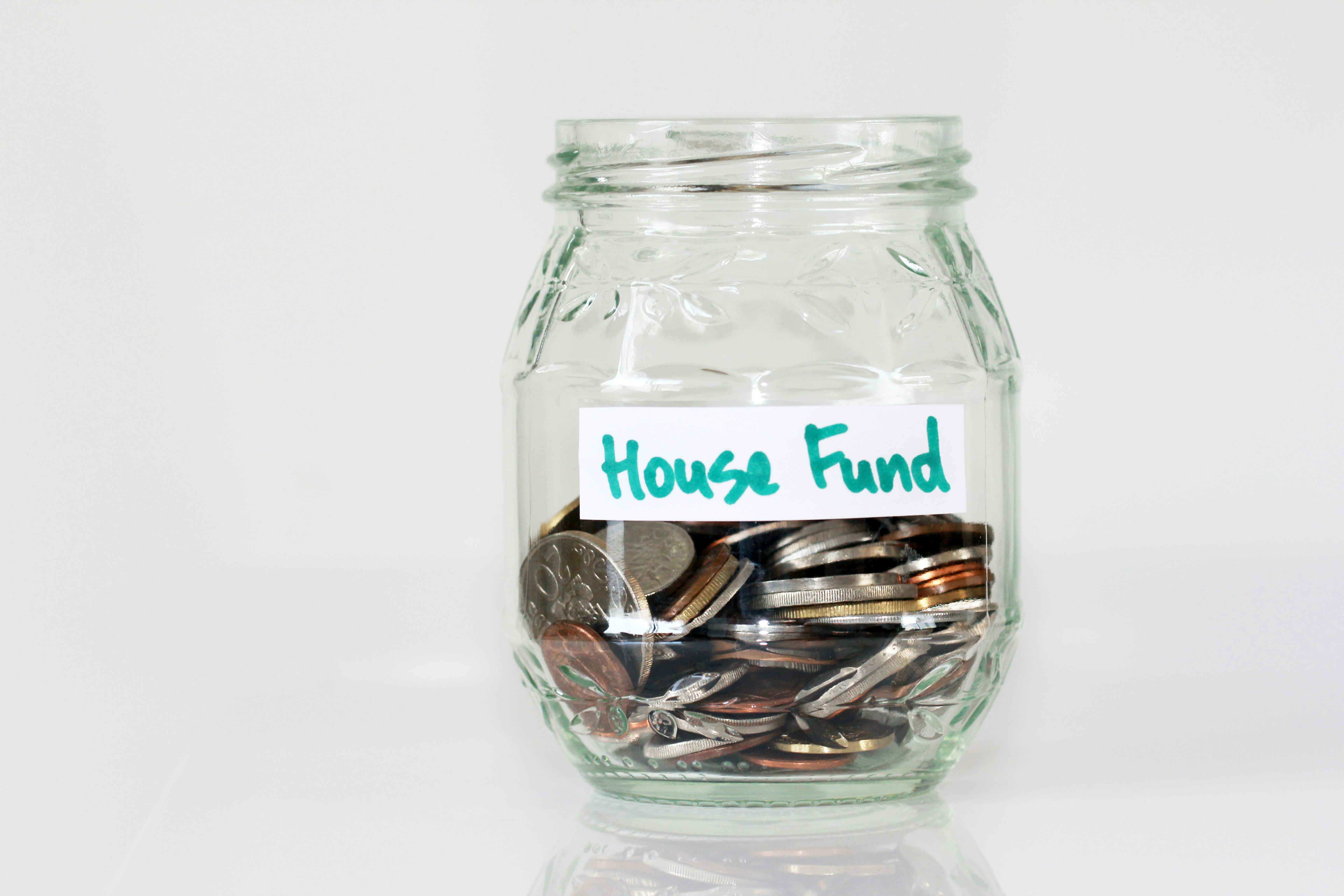 A jar of coins labelled House Fund — saving a deposit for your first home